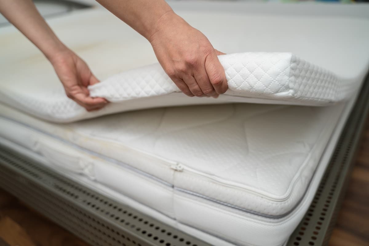 Mattress Topper Being Laid On Top Of The Bed